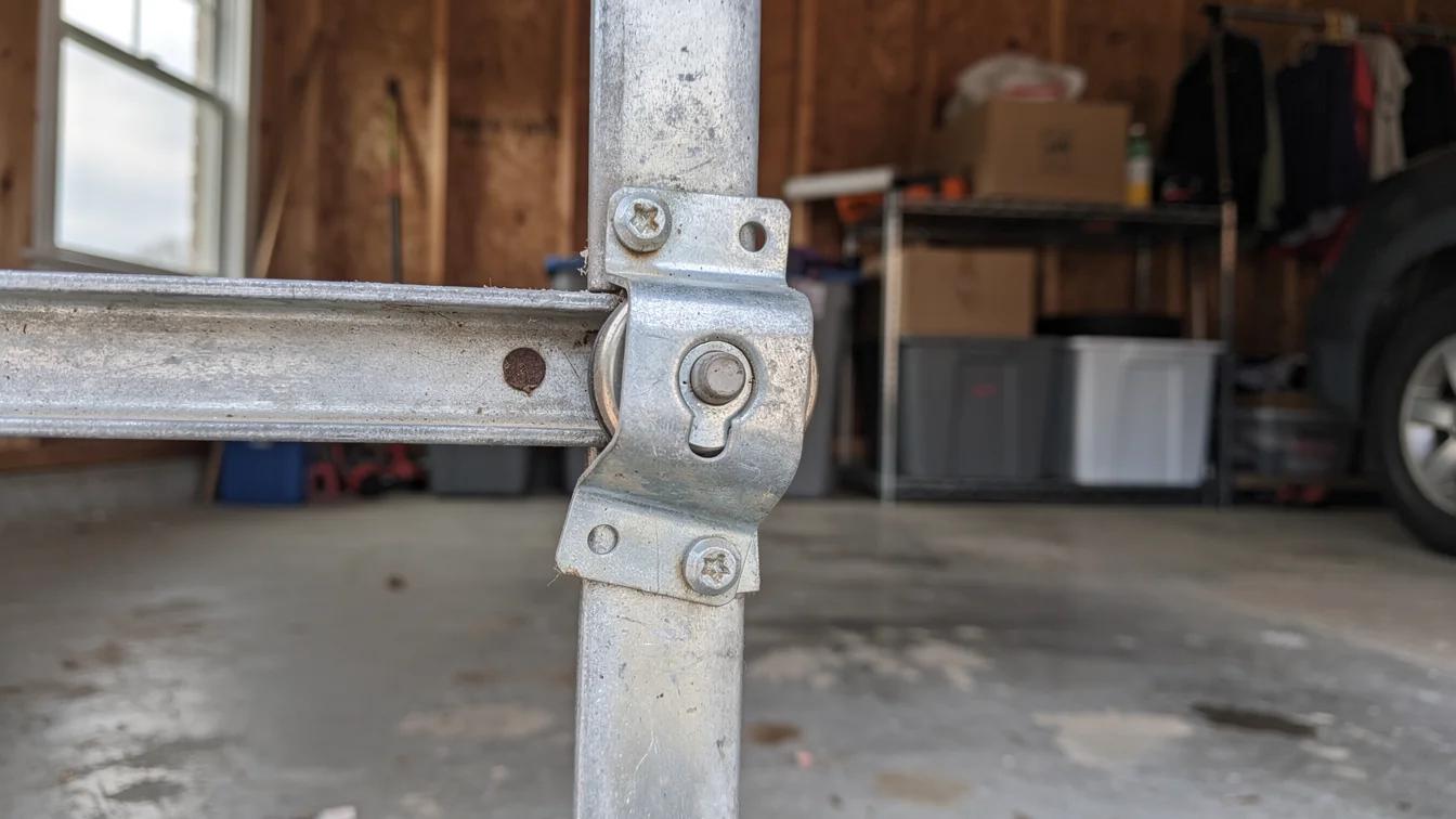 A metal garage door track is attached to a vertical metal pole.